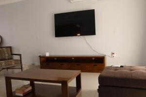 a living room with a couch and a tv on a wall at Tical Apartments in Lilongwe