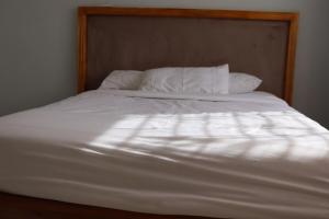 a white bed with white sheets and pillows at Tical Apartments in Lilongwe