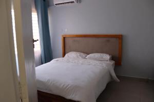 a bedroom with a white bed with a wooden headboard at Tical Apartments in Lilongwe