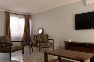 a living room with a tv and chairs and a table at Tical Apartments in Lilongwe