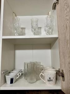 ein Schrank mit Gläsern und anderen Glasgegenständen darauf in der Unterkunft Apartament silver in Craiova