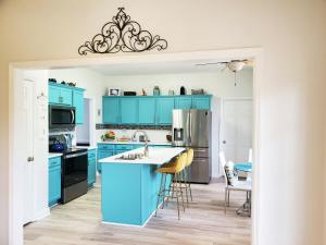 a kitchen with blue cabinets and a kitchen island with chairs at Coral Crest in Hampstead
