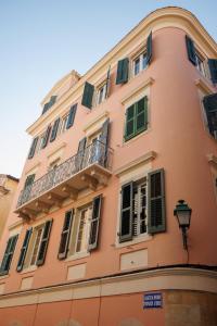 un bâtiment rose avec des fenêtres et un balcon dans l'établissement The Lucky 12, à Corfu