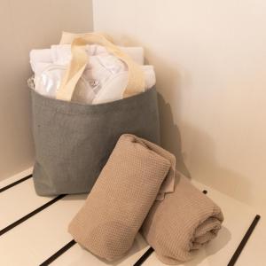 ブレッサノーネにあるecHo Apartments & SPAの床に置かれた衣類とタオルの入ったバッグ