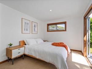 a white bedroom with a bed and a window at Summer Palms - Tairua Holiday Home in Tairua