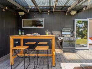 an outdoor kitchen with a bar and stools at Summer Palms - Tairua Holiday Home in Tairua