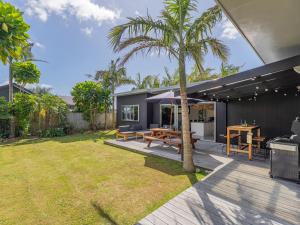 a backyard with a picnic table and a palm tree at Summer Palms - Tairua Holiday Home in Tairua