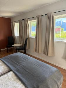 ein Schlafzimmer mit einem Bett und zwei Fenstern in der Unterkunft Solstad in Senja