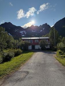 Ein Haus an einer Straße mit Bergen im Hintergrund in der Unterkunft Solstad in Senja