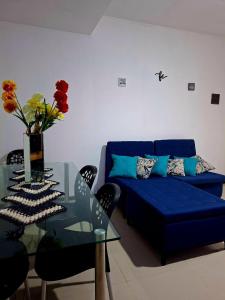a living room with a blue couch and a glass table at Temporada na Praia do Trevo - Rio das Ostras, RJ in Rio das Ostras
