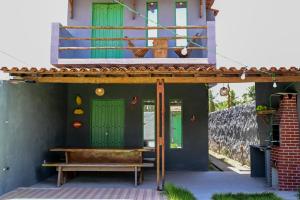 eine Veranda eines Hauses mit grünen Türen und einer Bank in der Unterkunft Casa Brisa das Aguas Piscina e Churrasqueira in Tatuamunha