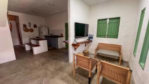 ein Zimmer mit Stühlen und eine Küche mit einem grünen Fenster in der Unterkunft Casa Brisa das Aguas Piscina e Churrasqueira in Tatuamunha