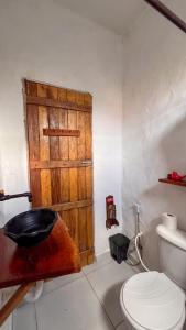 ein Badezimmer mit Toilette und Holztür in der Unterkunft Casa Brisa das Aguas Piscina e Churrasqueira in Tatuamunha + 21 Fotos