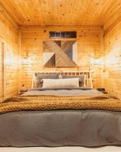 ein Schlafzimmer mit einem großen Bett an einer Holzwand in der Unterkunft Creekside Hocking Hills Cabin-Game Shed Hot Tub in South Bloomingville