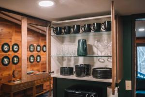ein Regal mit Tellern und Gläsern darauf in der Unterkunft Emerald Edge Hocking Hills Midcentury Cabin & Hot Tub in South Bloomingville