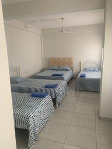 a room with four beds with blue and white sheets at Hotel Las Colonias in Encarnación