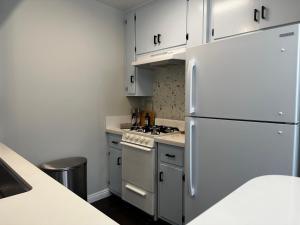 a kitchen with white cabinets and a white refrigerator at The Nest Manhattan Beach, Partial Ocean View in Los Angeles