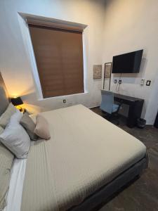 a bedroom with a bed and a desk and a television at Hotel Boutique Casa Zafra in Campeche
