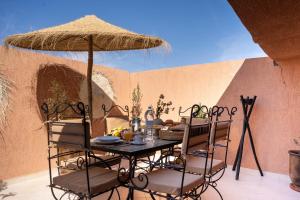 a table with chairs and an umbrella on a patio at Lyxig oas i Medina och fantastisk terrass in Marrakech