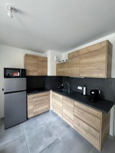 een keuken met houten kasten en een zwarte koelkast bij Studio Cosy Le Cocon au calme in Saint-Bonnet-de-Mure