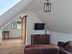 a living room with a couch and a television at Woodland studio in Stittenham