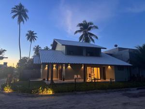 a house with palm trees in the background at pousada Maria da Fé in Vera Cruz de Itaparica
