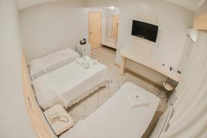 a white bedroom with a bed and a desk at Hotel Center in Xanxerê