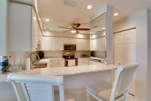 a kitchen with white cabinets and a counter with two chairs at Waterfront Punta Gorda Condo with Pool Access! in Burnt Store Marina