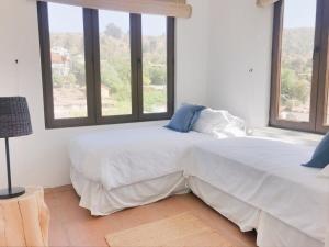 a bedroom with two beds and two windows at Casapueblo Rent Cachagua CP 23 in Cachagua +22 photos