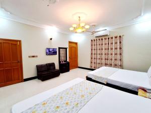 a bedroom with two beds and a chair at Family Rose Guest House Millennium in Karachi