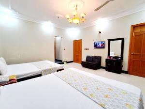 a hotel room with two beds and a television at Family Rose Guest House Millennium in Karachi +26 photos