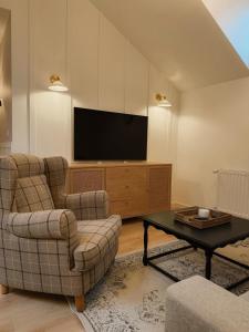 a living room with two chairs and a television at Apartamenty Guzik 32 in Krosno