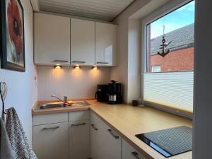 a kitchen with white cabinets and a sink and a window at Ferienwohnung Reede 19 in Butjadingen +3 photos