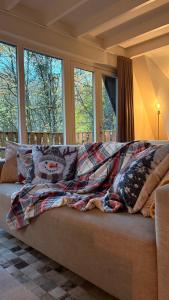 a blanket on a couch in a room with windows at Boshuisje Durbuy Nr6 in Durbuy