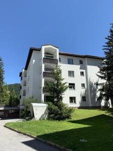 a white apartment building with a tree in front of it at Ferienwohnung Gian in Davos
