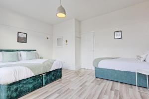 two beds in a bedroom with white walls and wooden floors at Bright & Luxury Home by the Sea, Great for Families & Contractors, Free Parking, Fast Wi-Fi, Guests 6, Ideal for Long Term Stays, Clark Property Estates in Southend-on-Sea +39 photos