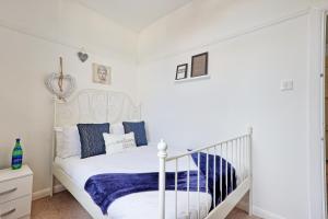a white bedroom with a white bed with blue pillows at Bright & Luxury Home by the Sea, Great for Families & Contractors, Free Parking, Fast Wi-Fi, Guests 6, Ideal for Long Term Stays, Clark Property Estates in Southend-on-Sea