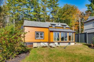 a small yellow house with some chairs in the yard at Direct Lake Access! Quiet Waukewan Retreat in Winona