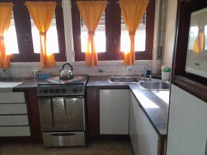 a kitchen with a stove and a sink and windows at La Casa de Oli in Chascomús