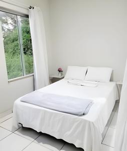 a white bed in a white bedroom with a window at Sobrado 6 amplo e confortável em condomínio in Corumbá