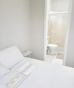 a white bedroom with a bed and a toilet at Sobrado 6 amplo e confortável em condomínio in Corumbá
