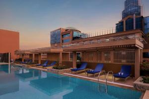 a swimming pool with blue chairs and a building at Marriott Executive Apartments Bengaluru UB City in Bengaluru