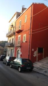 due auto parcheggiate di fronte a un edificio rosso di Reusia Holiday Home a Ragusa