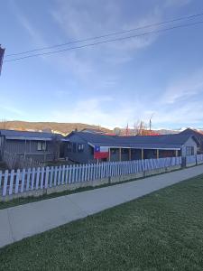 a white fence next to a train station at Mate Sur Hostal in Cochrane