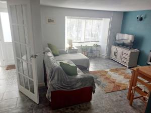 una camera da letto con un letto, un divano e una televisione di Cherry Cottage a Goodwick