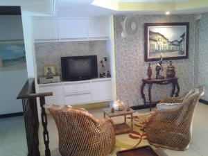 a living room with a television and two chairs at Itaparica - Praia de Ponta de Areia in Itaparica Town