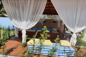 a bedroom with white curtains and a bed on a deck at Itaparica - Praia de Ponta de Areia in Itaparica Town