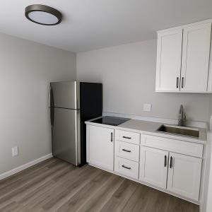 a kitchen with white cabinets and a stainless steel refrigerator at Empire Extended Stay in Webster
