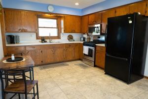 a kitchen with wooden cabinets and a black refrigerator at Convenient Countryside Oasis in Caledonia +17 photos