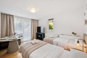a white room with two beds and a table and window at KRelax - Bad Wildbad - Moderne Wohnung für 6 Pers in Bad Wildbad